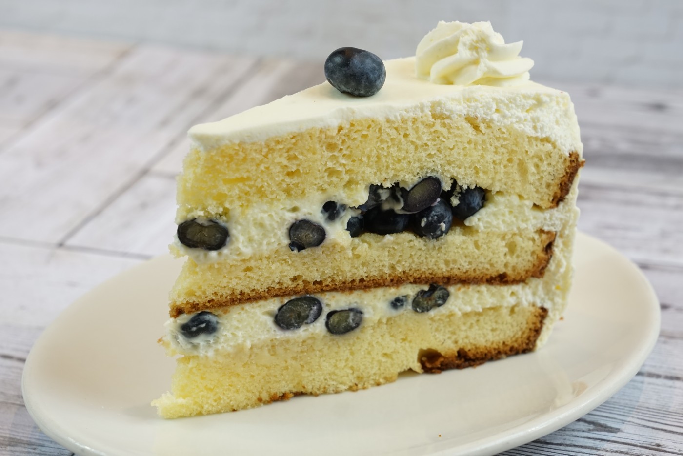 lemon blueberry cake slice savor the classic flavor of a traditional lemon blueberry cake slice at Mia's Bakery.
