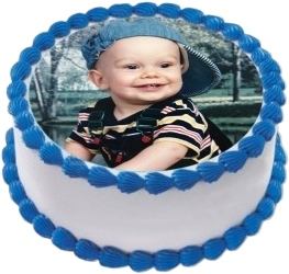 Round edible image cake featuring a smiling baby in striped shirt on a circular photo print topper. This custom photo cake from Mia's Bakery displays the adorable baby portrait centered on white frosting with blue ball piped borders along top and bottom edges. Perfect for first birthdays, baby celebrations, and milestone events with personalized edible photo printing.