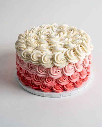 savor the flavor of custom Vintage White Cake with Pink Ombré Rosette at Mia's Bakery.