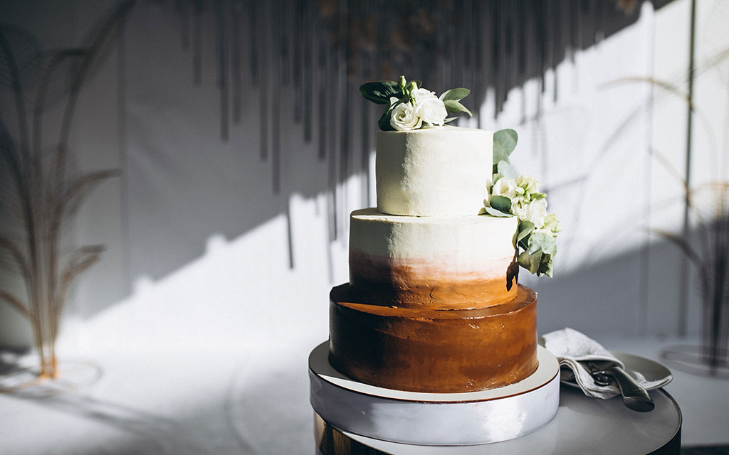 Three-tier wedding cake with ombre buttercream showing different wedding cake flavors per tier