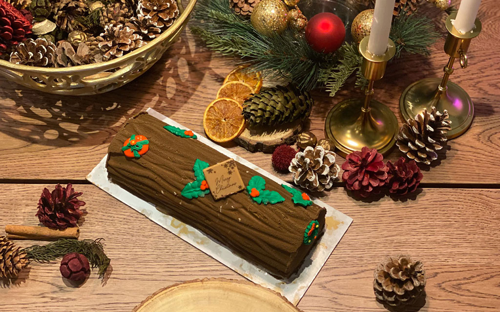 Seasonal desserts for Christmas featuring Bûche de Noël yule log cake with chocolate bark texture and festive decorations