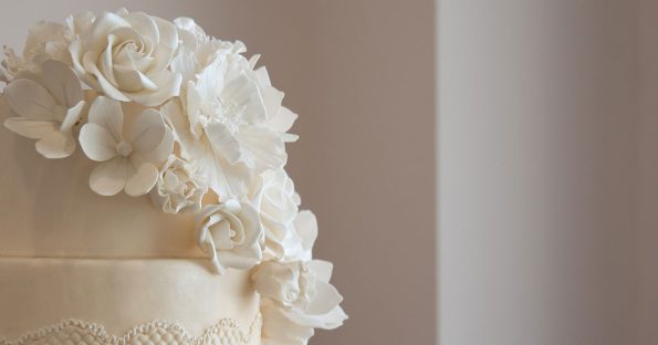 Wedding cake ideas featuring elegant white tiered cake with cascading sugar flowers and delicate lace piping detail