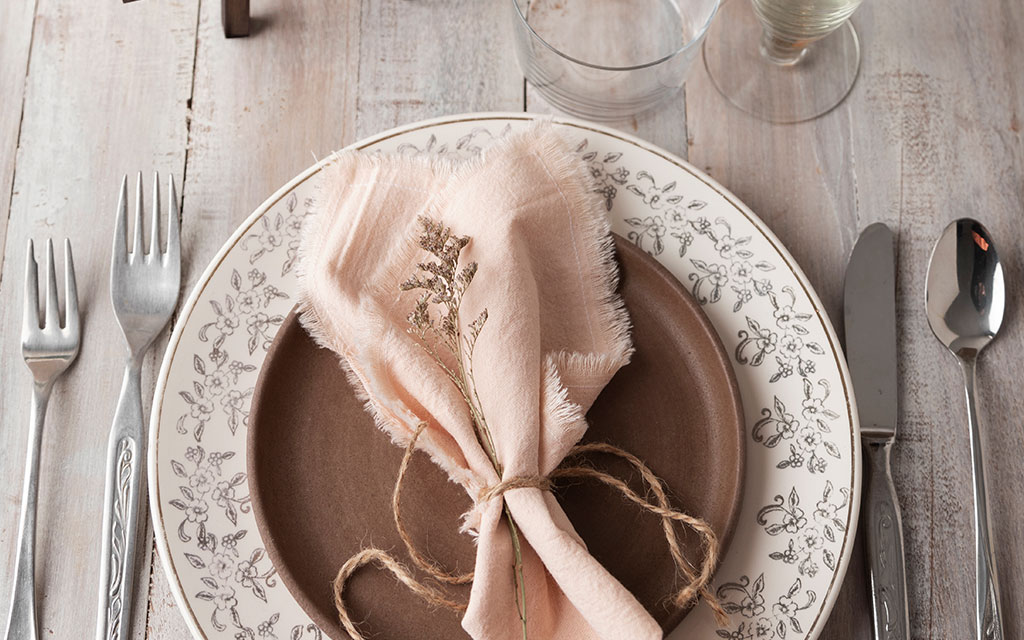 Rustic fall wedding table setting with blush napkin, dried flowers, and vintage china on whitewashed wood